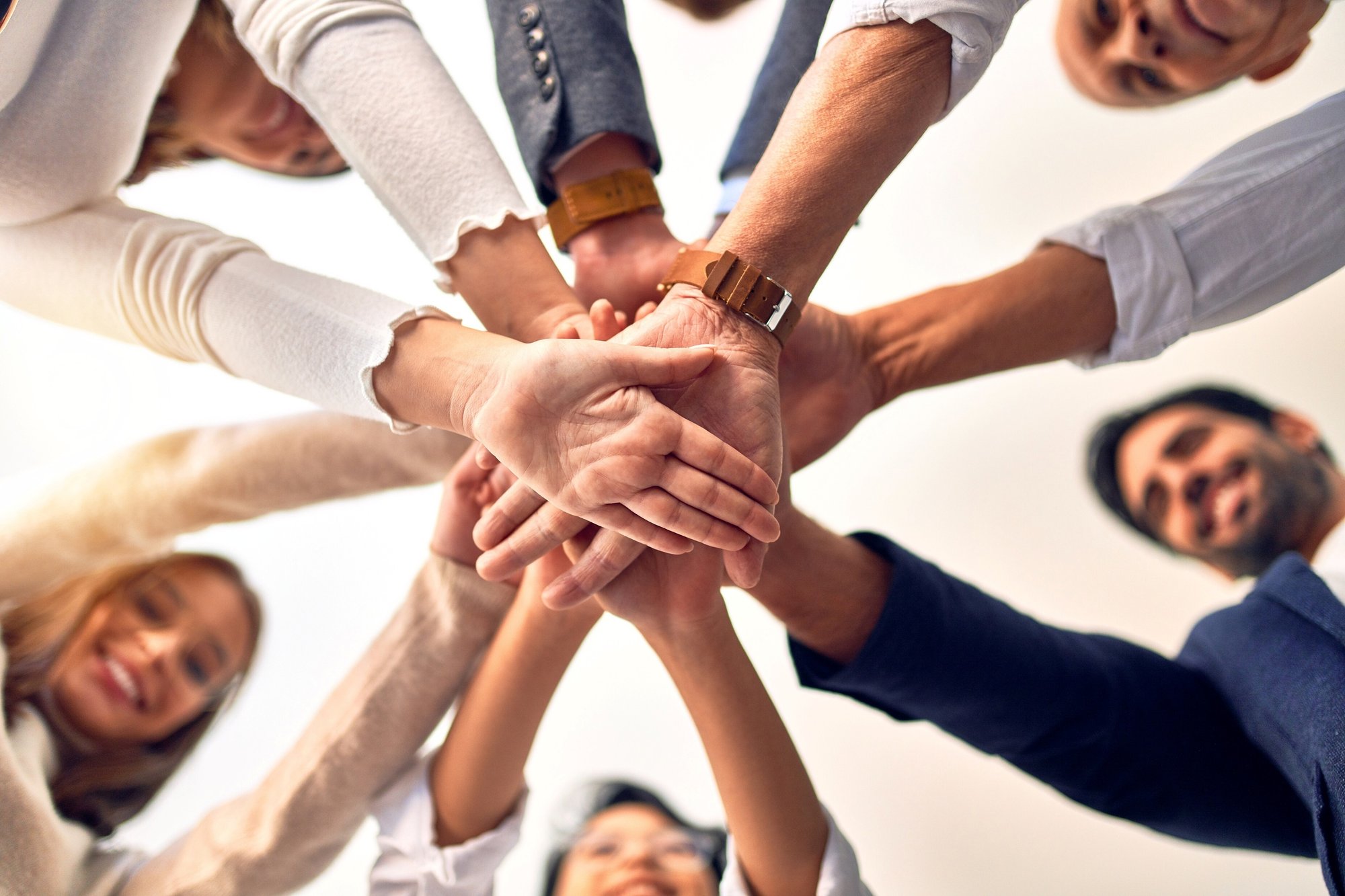 Gruppo di persone che si tengono le mani in segno di squadra, vista dal basso verso l'alto.